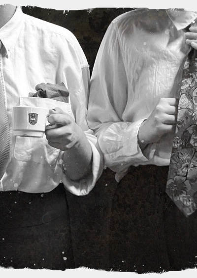 To mennesker iført hvid skjorte, slips og holder kaffekop